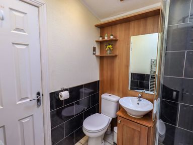 A bathroom with a toilet sink mirror and corner shelves near Carnforth