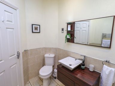 A bathroom with a toilet a sink on a wooden vanity and a mirror at Otters Reach near Carnforth