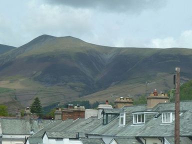 Rooftops of houses with chimneys and antennas with hills in the background at Capella Cottage in Keswick