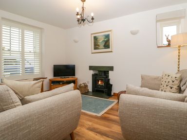 A living room with a television and fireplace at Capella Cottage in Keswick