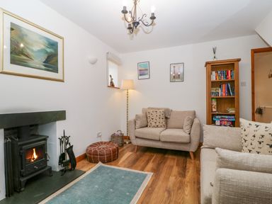 A living room with a fireplace and bookshelves at Capella Cottage in Keswick