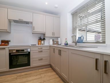 A kitchen with cabinets, oven, sink, and utensils at Capella Cottage in Keswick