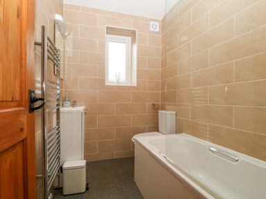 A bathroom with a tub, toilet, and sink at Capella Cottage in Keswick