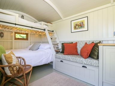 A small room with a bunk bed a wicker chair and a cushioned bench with pillows at Blackthorn South Leigh near Witney
