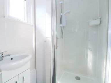 A bathroom with a white sink cabinet and a glass door shower at Number 19 in Cromer