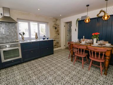 A kitchen with cabinets, a dining table and chairs at La Bastille in Maenclochog