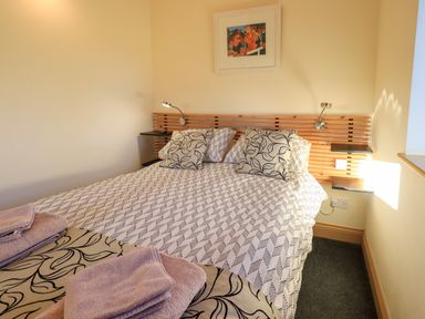 A bedroom with a double bed two bedside lamps and a framed picture above the headboard at Cedrus Lodge in Skelton near Penrith
