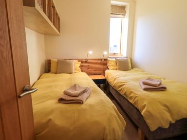 A bedroom with two single beds and yellow bedding at Cedrus Lodge in Skelton near Penrith