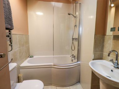 A bathroom with a bathtub and shower, a toilet, and a sink at Cedrus Lodge in Skelton near Penrith