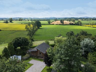 A view of fields and trees with a house in the foreground at Cedrus Lodge in Skelton near Penrith