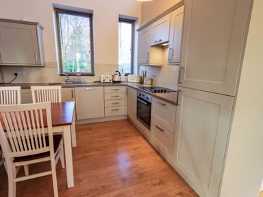 A kitchen with wooden floor cabinets appliances and dining table and chairs at Larch Lodge Skelton near Penrith