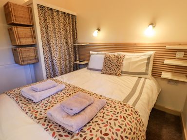 A bedroom with a bed folded towels and patterned cushions at Larch Lodge in Skelton near Penrith
