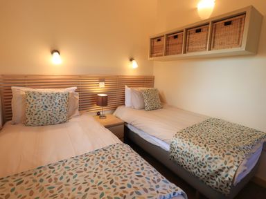 A bedroom with two single beds with patterned throws and cushions at Larch Lodge in Skelton near Penrith