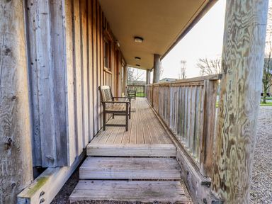 A wooden porch with two chairs and wooden railings at Larch Lodge in Skelton near Penrith