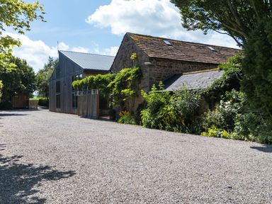 An outdoor area with a gravel driveway and trees at Larch Lodge in Skelton near Penrith