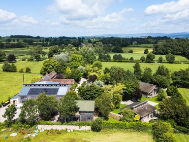 An aerial view of a property with buildings and fields at Larch Lodge in Skelton near Penrith