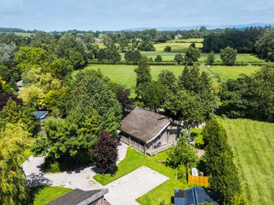 A view of a building surrounded by trees and grass at Larch Lodge in Skelton near Penrith