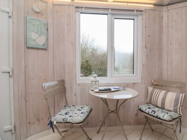 A small dining area with two chairs and a round table in a room with wooden panel walls near Hartland