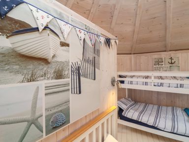 A bedroom with wooden bunk beds striped bedding nautical wall decorations and bunting at Barley Bay near Hartland