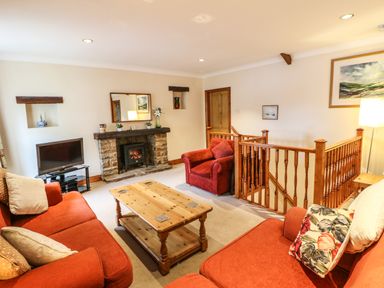 A living room with red sofas wooden coffee table fireplace and a television at Crescent Cottage in Haltwhistle near Hadrians Wall