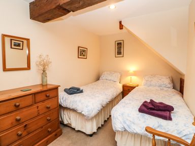 A bedroom with two single beds a wooden dresser and a wooden chair at Crescent Cottage in Haltwhistle near Hadrians Wall