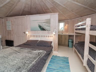 A bedroom with a double bed and bunk beds next to a small kitchen area at Spekes Mill near Hartland