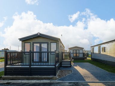 Two mobile homes with porches and paved driveways in an outdoor setting at The Sea Lodge in Bacton near Walcott