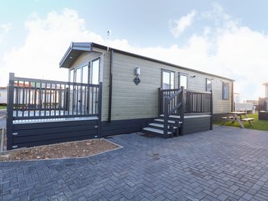 A static caravan with steps and railings on a paved driveway at The Sea Lodge in Bacton near Walcott