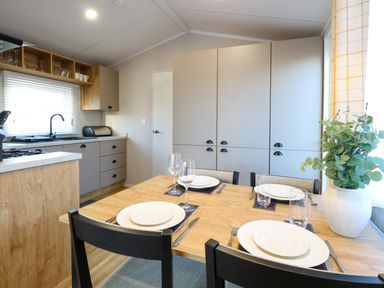 A kitchen with dining table set with plates glasses and cutlery and cabinets in the background at The Sea Lodge in Bacton near Walcott