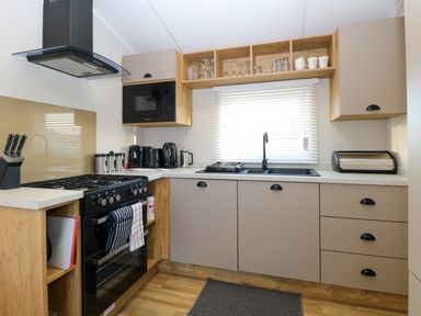 A kitchen with gas stove oven dishwasher microwave sink and various kitchen appliances at The Sea Lodge in Bacton near Walcott