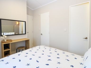 A bedroom with a bed with sea creature patterned bedding a wooden desk with a stool and a wall mirror at The Sea Lodge in Bacton near Walcott