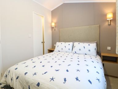 A bedroom with a bed with sea creature patterned bedding and wall lamps at The Sea Lodge in Bacton near Walcott