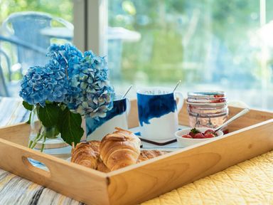 A tray with croissants, flowers, mugs, jam, and strawberries at Pentire St Minver