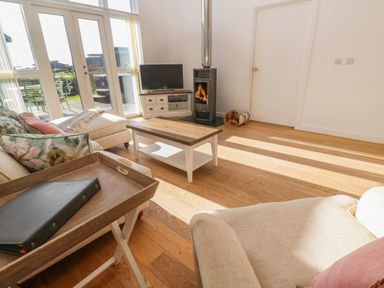 A living room with sofas cushions a coffee table a TV and a wood stove at Una Lodge 77 in Carbis Bay
