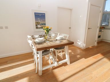 A dining area with a wooden table set for six and white chairs at Una Lodge 77 in Carbis Bay