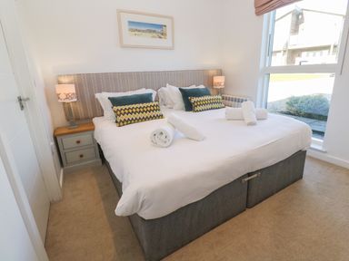 A bedroom with a double bed pillows rolled towels bedside tables lamps and a window at Una Lodge 77 in Carbis Bay