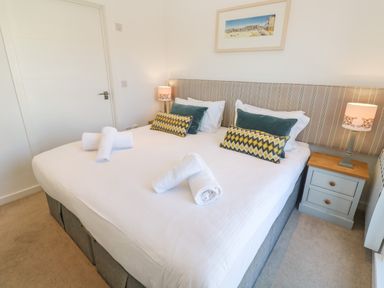 A bedroom with a double bed two bedside tables and lamps and a framed picture on the wall at Una Lodge 77 in Carbis Bay