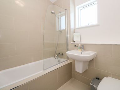 A bathroom with a bathtub shower combination and a pedestal sink at Una Lodge 77 in Carbis Bay