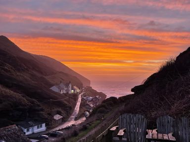 A coastal village with houses along a winding road and ocean in the background at Little Ruffo Trebarwith near Tintagel