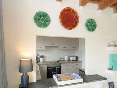 A kitchen with gray cabinets and countertop with a toaster kettle and oven at Little Ruffo Trebarwith near Tintagel