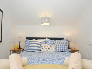 A bedroom with a bed with patterned pillows and nightstands with lamps at Little Ruffo Trebarwith near Tintagel