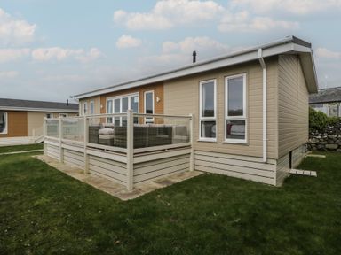 A house with a deck and grass in front at Platinum Lodge (503) Talybont