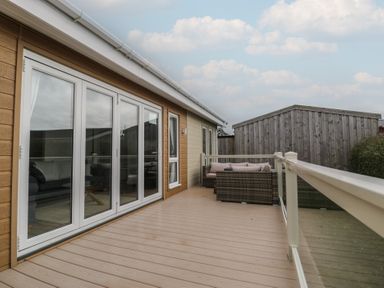 A deck area with sliding doors and outdoor furniture at Platinum Lodge (503) Talybont