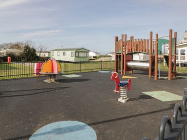 A playground with a slide, seesaw, and spring riders at Platinum Lodge (503) Talybont