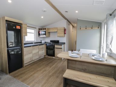 A kitchen with refrigerator, sink, and dining table at Lido Silver Plus 111 Prestatyn