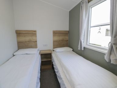 A bedroom with two single beds and a window at Lido Silver Plus 111 Prestatyn