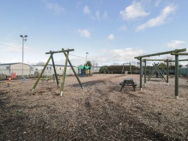 A playground with swings and play equipment at Lido Silver Plus 111 Prestatyn