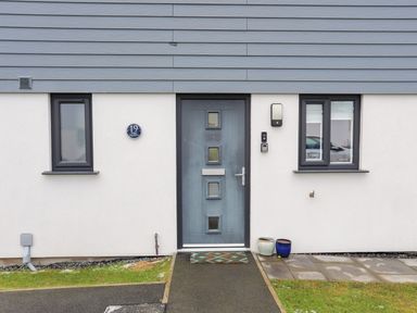 A front door with two windows and two pots outside at 19 Parc Delfryn in Benllech