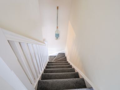 A carpeted staircase with white banister and a decorative paddle on the wall at 19 Parc Delfryn in Benllech