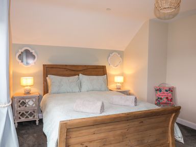 A bedroom with a wooden bed and two bedside tables with lamps at 19 Parc Delfryn in Benllech